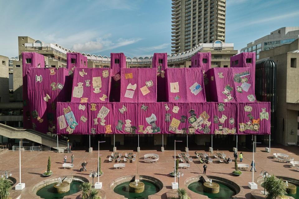 Gut angezogen Spätestens seit seinem Auftritt auf der Venedig-Biennale 2015, als er das Arsenale mit gebrauchten Kakaobohnensäcken einkleidete, ist Ibrahim Mahama bekannt für seine spektakulären Gebäudeverhüllungen. In London hat der Ghanaer jetzt das Barbican Centre mit 2000 Quadratmetern rosa und lila Stoffbahnen bedeckt. Unser Bild zeigt "Purple Hibiscus", benannt nach einem Roman von Chimamanda Ngozi Adichie. Die Stoffe wurden in Zusammenarbeit mit Kunsthandwerkern aus Tamale in Ghana gewebt und genäht,