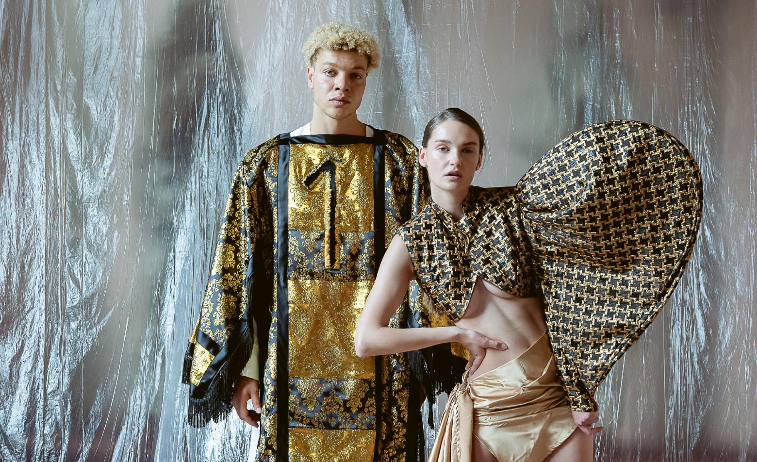 Zwei Models präsentieren Kleidung mit den Designs von Yvonne von Brandis (l) und Giuliana Schmidt (r) für die ungewöhnliche Schau "Der goldene Faden", die unter anderem sexuellen Missbrauch und Schuld thematisiert
