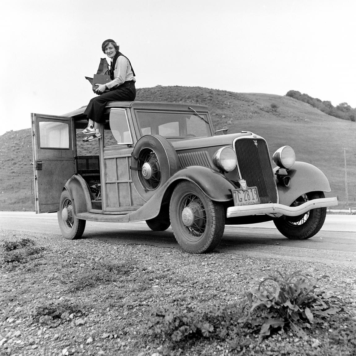 Dorothea Lange (1895-1965) sitzt mit einer Graflex Kamera auf einem Ford V8 in Kalifornien