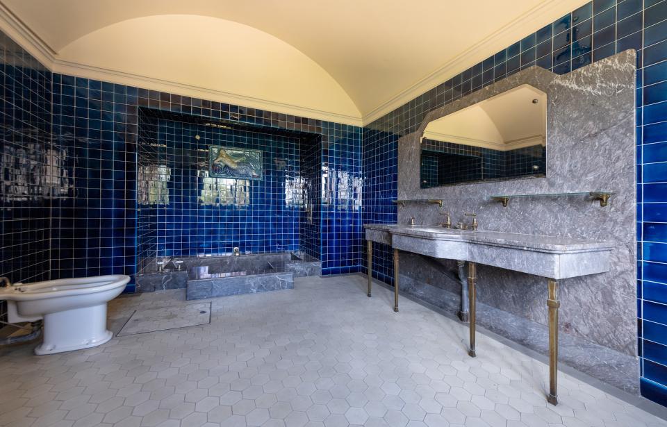  Das Badezimmer mit in den Boden eingelassener Badewanne, Bidet, Marmortisch mit zwei Waschbecken und blauen Fliesen