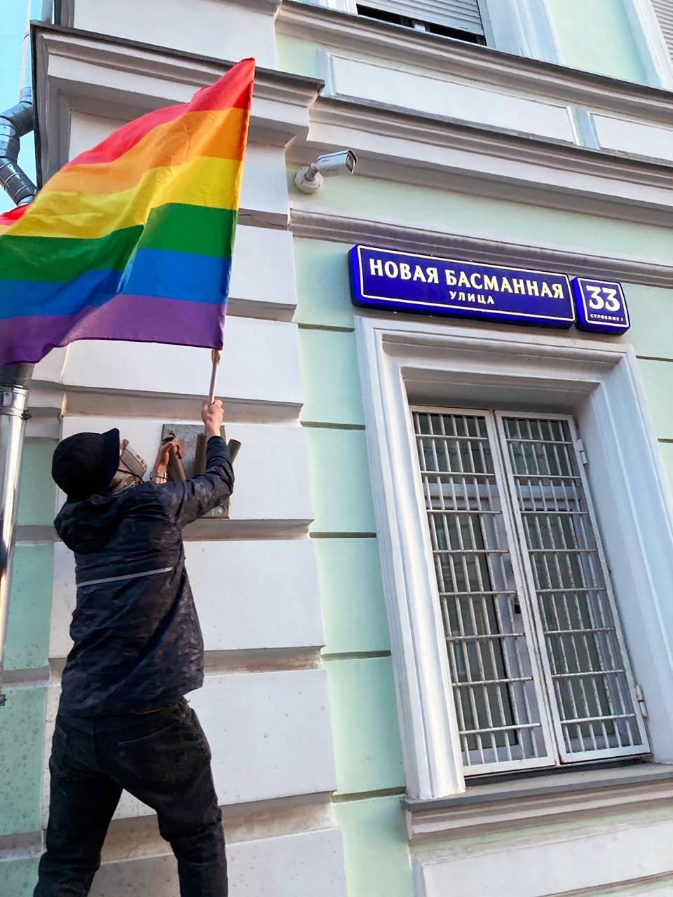 Ein Mitglied von Pussy Riot bringt an einem Polizeigebäude eine Regenbogenflagge an