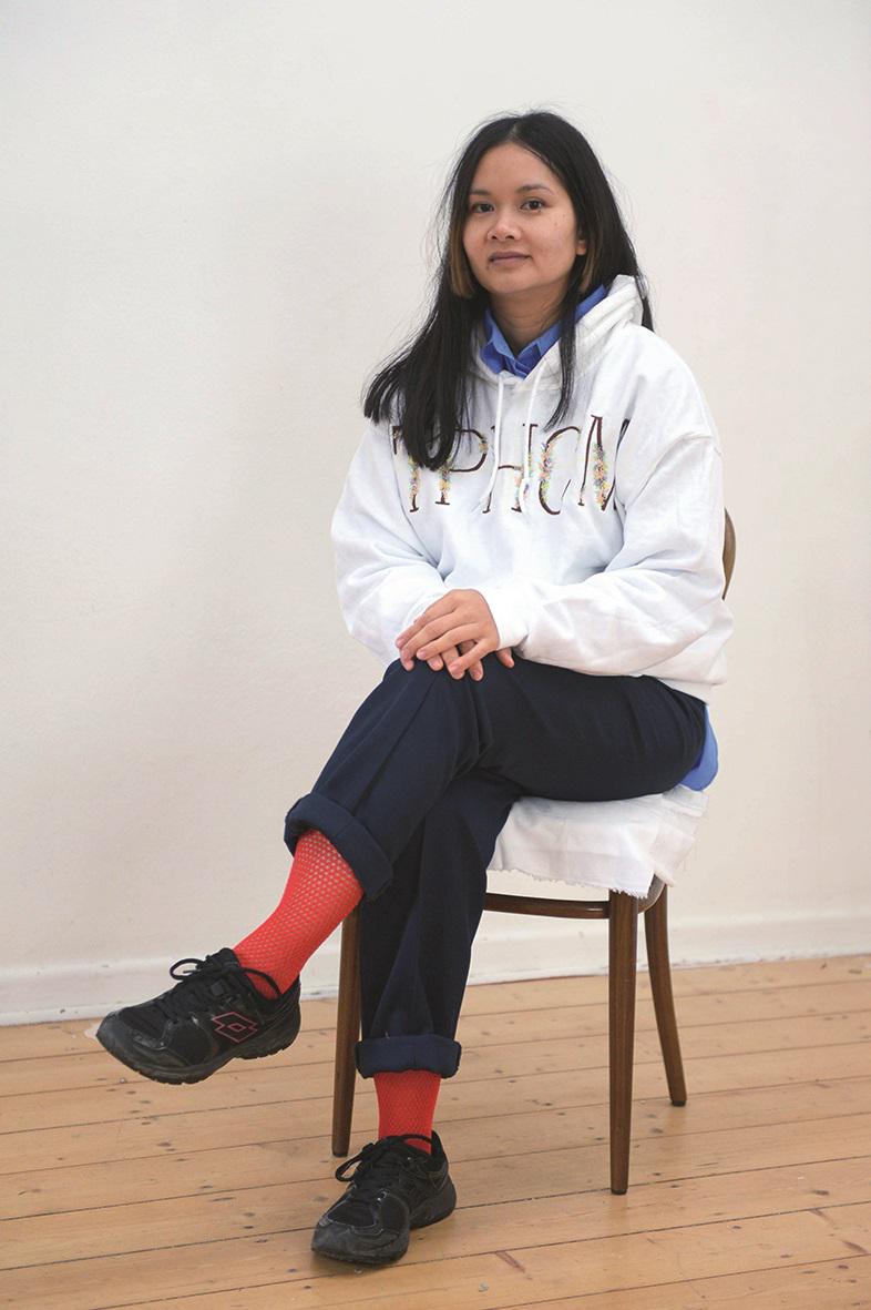 Die Essener Künstlerin Phung-Tien Phan auf einem Stuhl sitzend