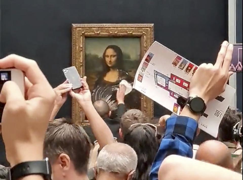 Dieses Videostandbild zeigt einen Mitarbeiter des Louvre, der Sahnekuchen von der Vitrine wischt, welche die "Mona Lisa" schützt. Ein möglicherweise verwirrter Besucher hat das hinter Panzerglas ausgestellte Bild mit einem Tortenstück beworfen. Das weltberühmte Gemälde ist bei der Attacke am Sonntag aber nicht beschädigt worden