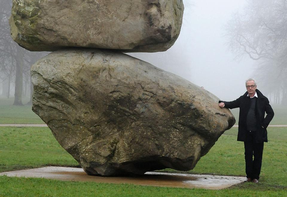 Der Schweizer Künstler Peter Fischli posiert 2013 mit einem riesigen künstlichen Felsen mit dem Titel "Rock on Top of Another Rock" von Peter Fischli und David Weiss, Serpentine Gallery, London