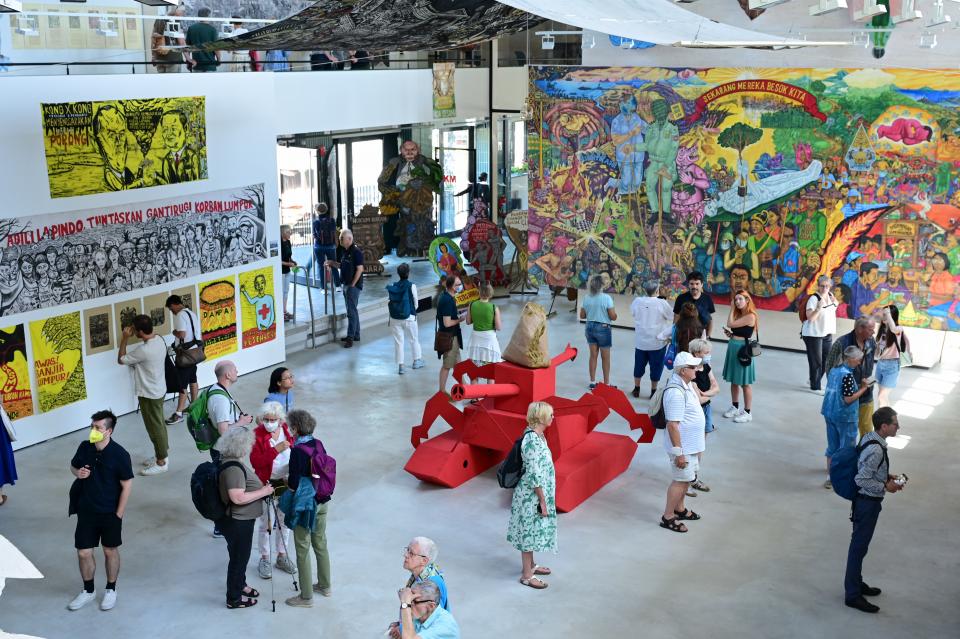 Besucherinnen und Besucher stehen im Kasseler Hallenbad-Ost, in dem das indonesischen Künstlerkollektiv Taring Padi ausstellt