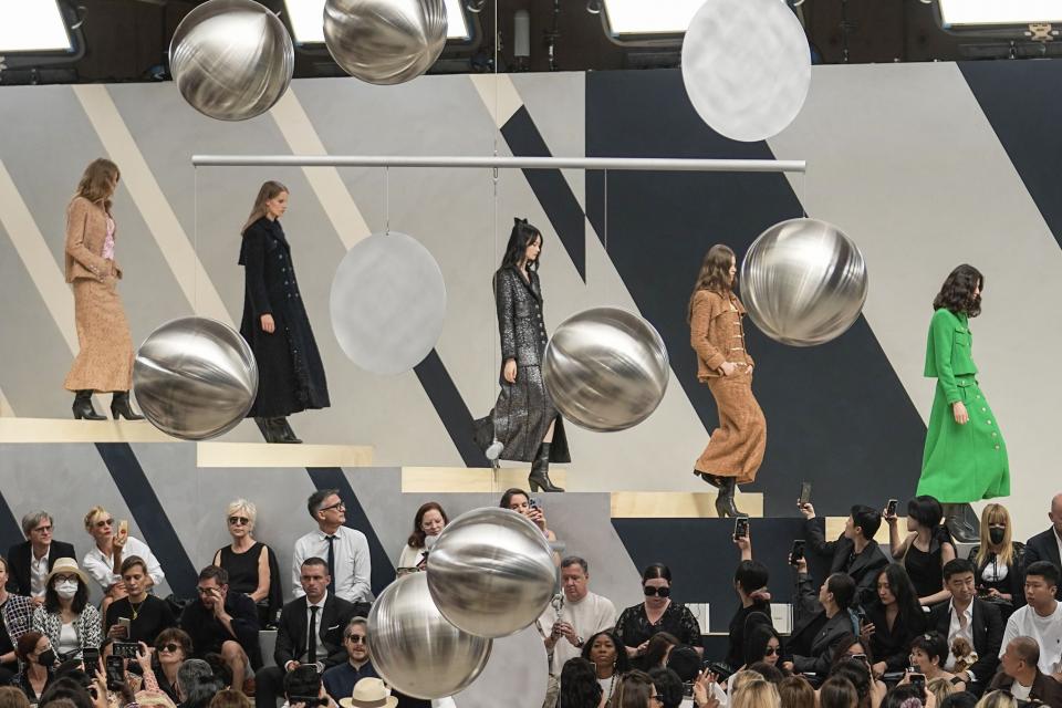 Models tragen Kreationen von Chanel bei den Haute-Couture-Schauen für Herbst/Winter 2022-2023 in einem Reitstall am Bois de Boulogne; rechts ein Model im knallgrünen Tweed-Ensemble aus langem Rock und Blazer mit aufgesetzten Taschen