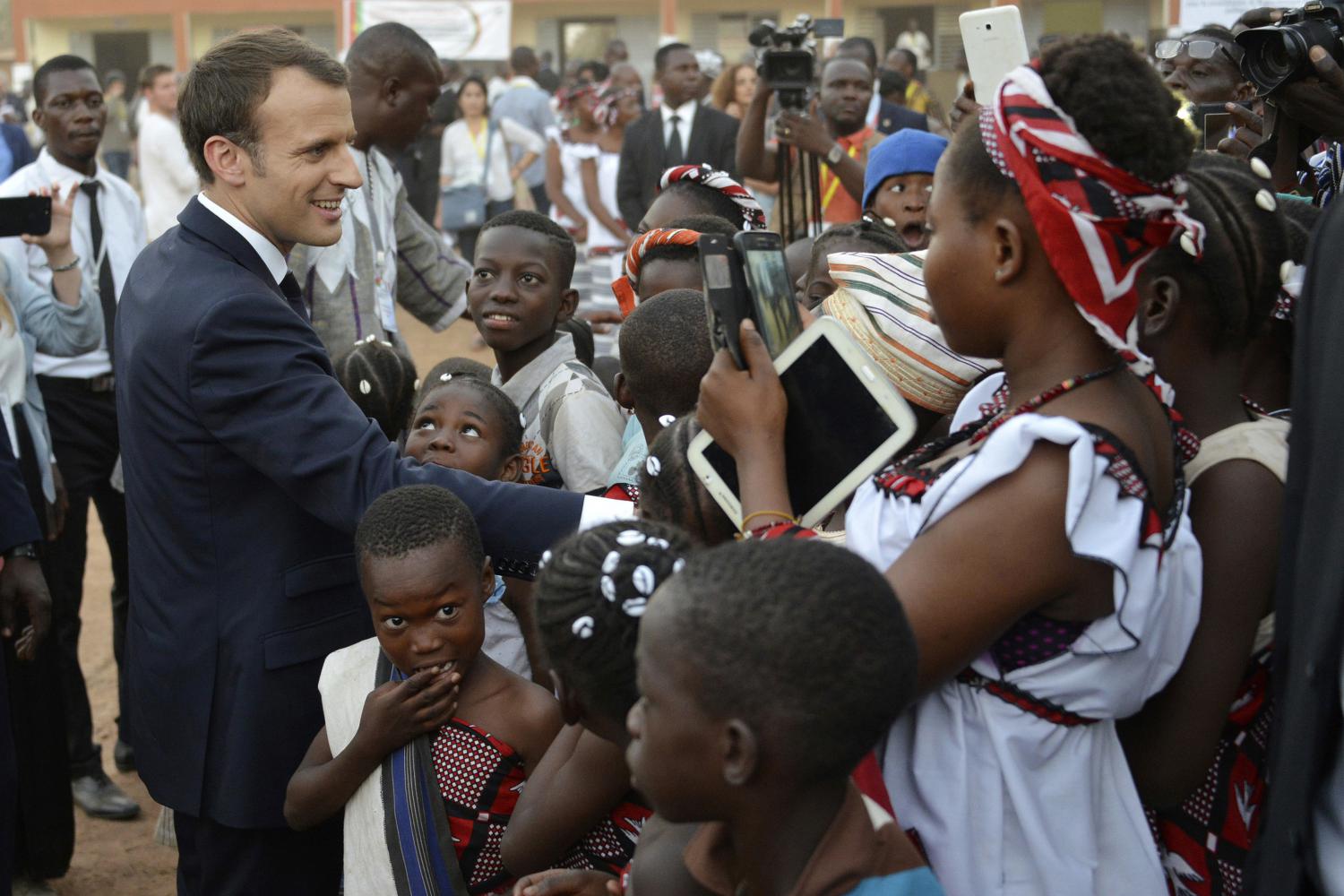 Emmanuel Macron, Präsident von Frankreich, begrüßt Schülerinnen und Schüler beim Besuch einer Schule in Burkina Fasos Hauptstadt. Frankreichs Staatschef hat 2017 die Rückgabe von Kolonialkunst versprochen