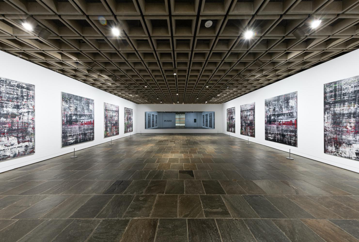 Blick in die Ausstellung "Gerhard Richter: Painting After All" im New Yorker Met Breuer: Der "Birkenau"-Saal umfasst vier Gemälde auf der linken Seite, vier exakte Tintenstrahl-Reproduktionen auf der rechten Seite, eine Spiegelarbeit auf der Rückseite und die Quellfotografien aus dem Vernichtungslager, die in der Spiegelung des Spiegels zu sehen sind