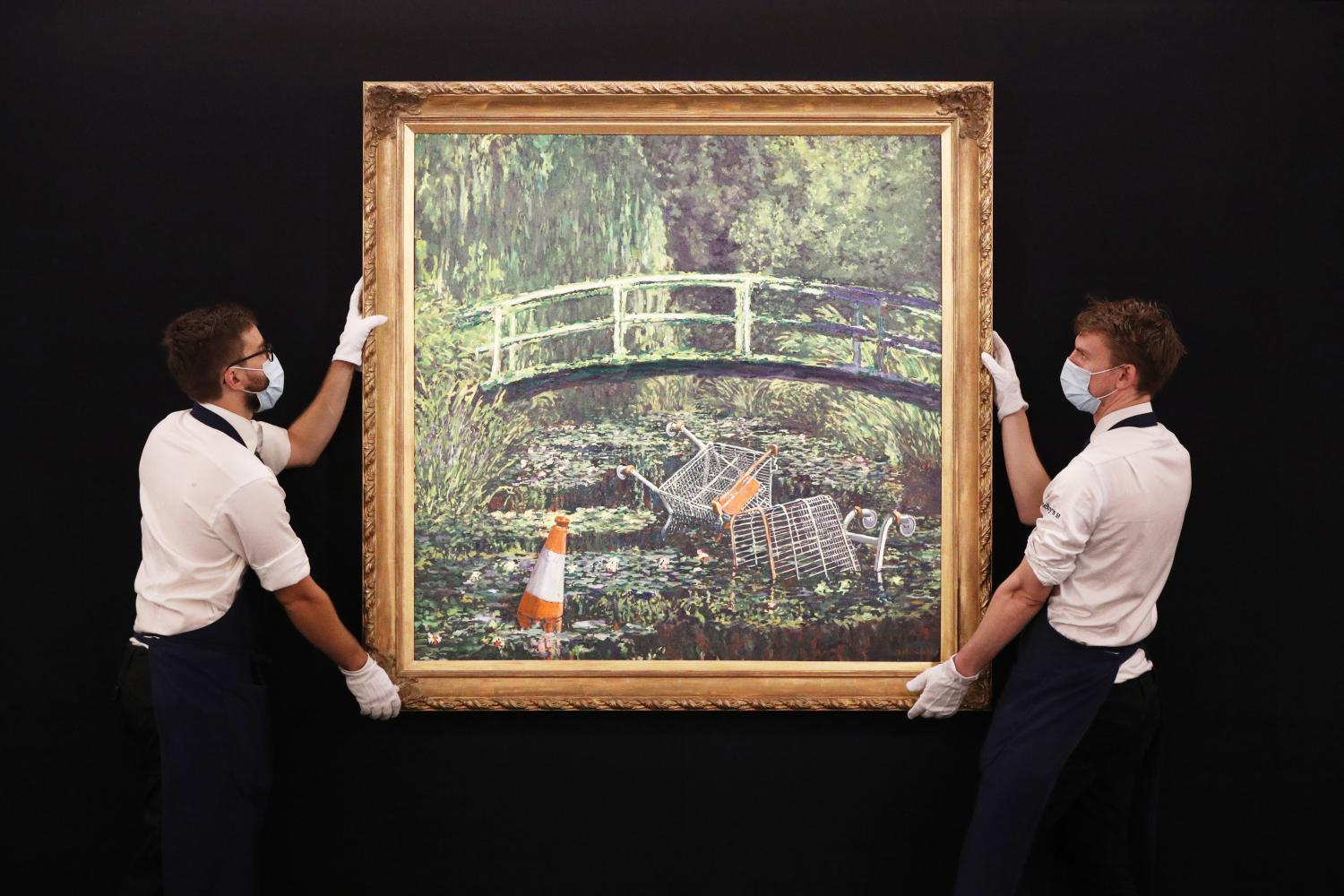 Zwei Angestellte im Auktionshaus Sotheby's halten das Gemälde "Show Me The Monet" von Banksy