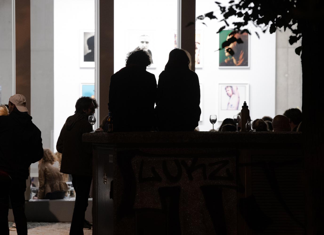 Menschen sitzen am Abend vor einer Berliner Galerie