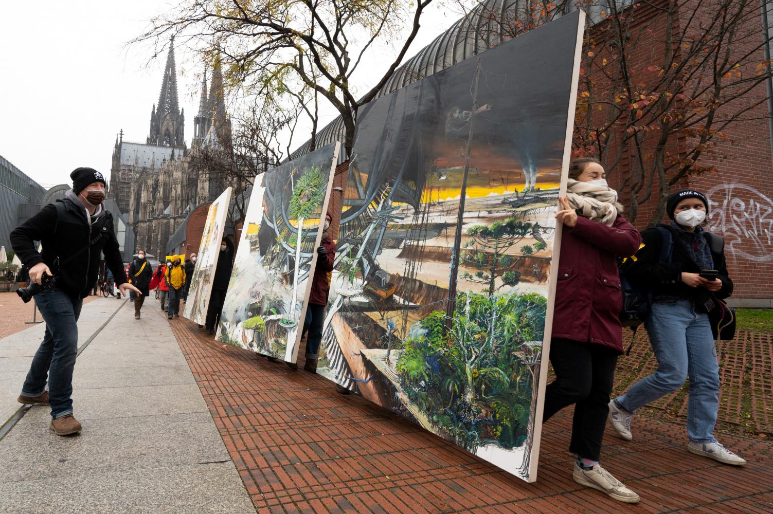 Klimaaktivisten tragen das Bild "Das Große Gelingen", 2021, des Künstlerpaares Helge & Saxana durch Köln