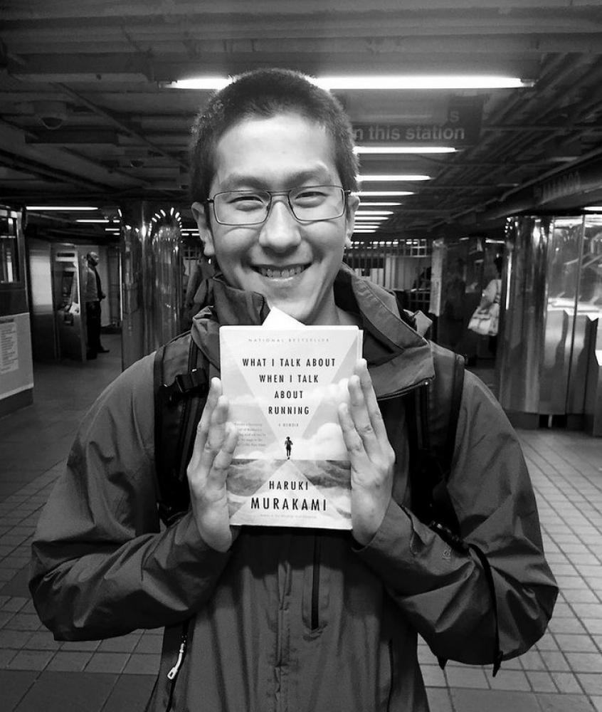 Mann in der New Yorker U-Bahn mit Buch "What I Talk About When I Talk About Running" von Haruki Murakami