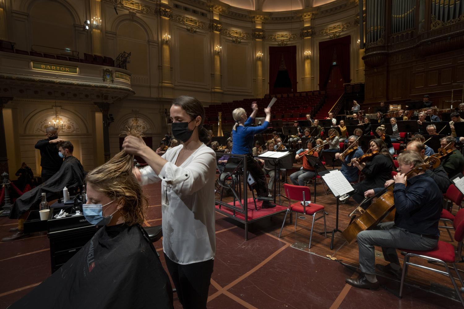 Menschen lassen sich während einer Probe im Concertgebouw in Amsterdam auf der Bühne die Haare schneiden