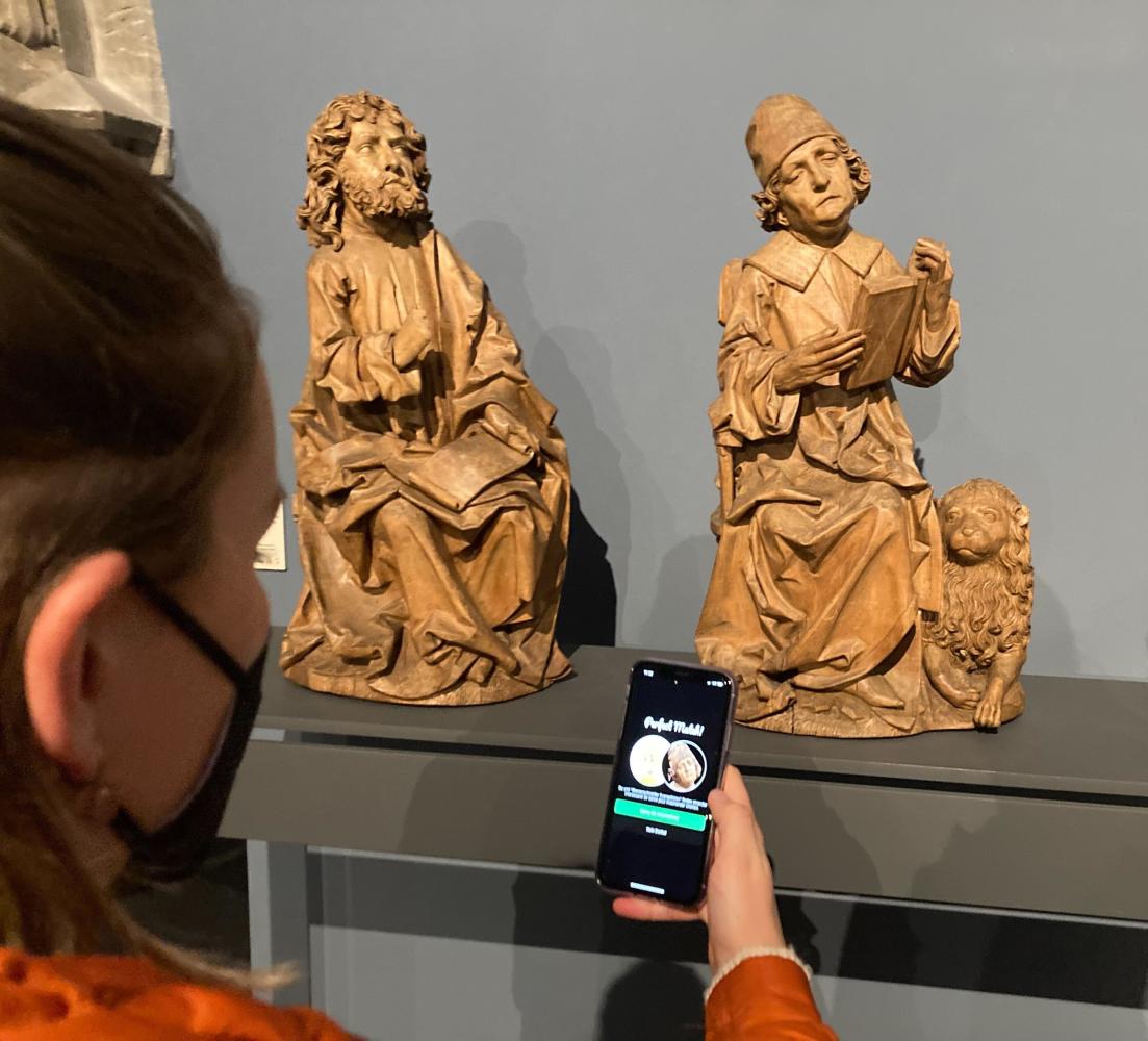 Eine Frau steht im Bode-Museum mit ihrem Handy vor der Figur des Markus (r), einer der zwischen 1490 und 1492 entstandenen "Vier Evangelisten" von Tilman Riemenschneider