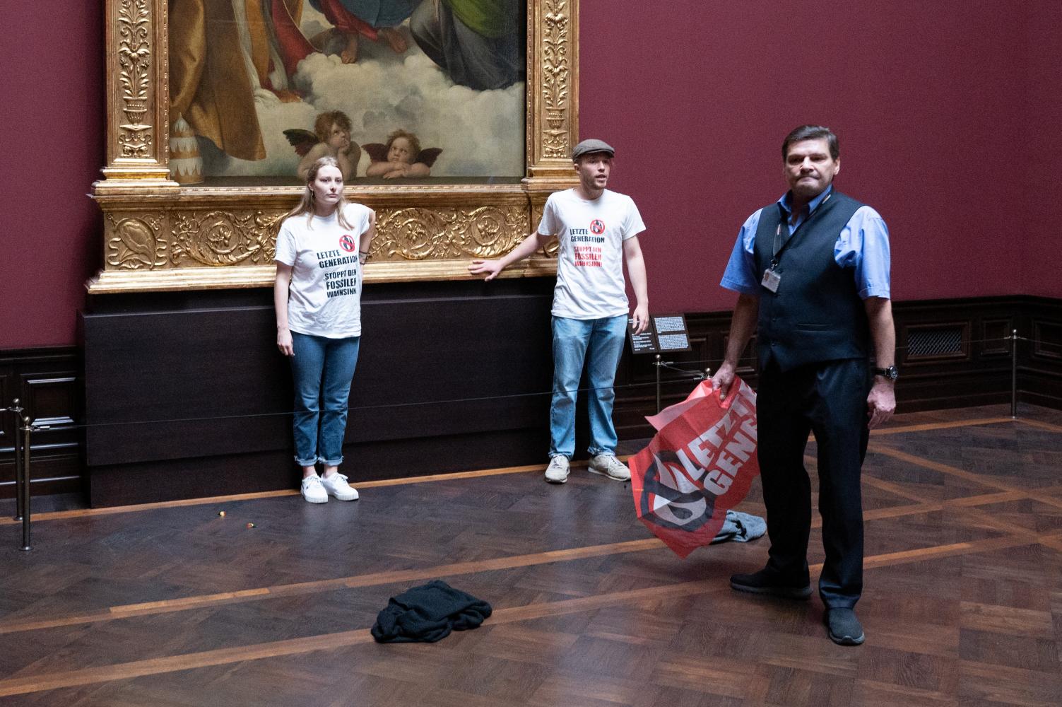 Zwei Umweltaktivisten der Gruppe "Letzte Generation" stehen in der Gemäldegalerie Alte Meister an dem Gemälde "Sixtinische Madonna" von Raffael. Die Klebe-Attacke verursachte Schäden in fünfstelliger Höhe