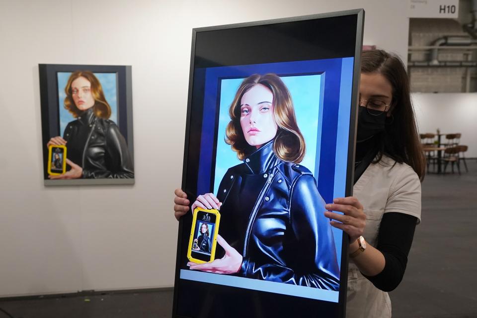 Eine Mitarbeiterin von der Galerie MeetFrida Art im November auf der Hamburger Kunstmesse Affordable Art Fair mit dem NFT-Kunstwerk “Abyss“ von der Künstlerin Roxanne Sauriol, im Hintergrund ein Print des Kunstwerks