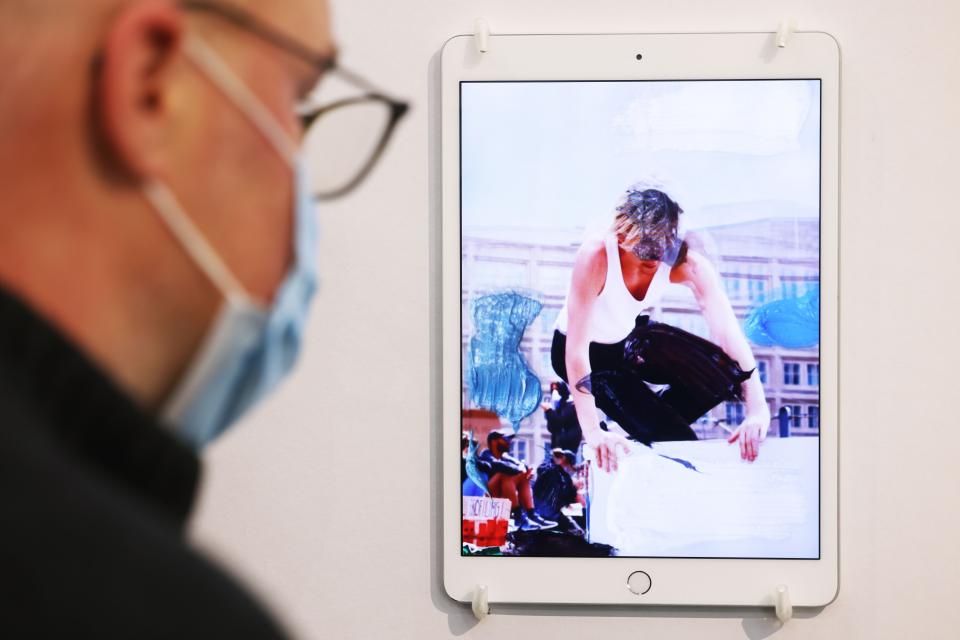 Ein Mann betrachtet auf der Kölner Kunstmesse Art Cologne ein NFT des Künstler Erik Schmidt auf einem iPad auf dem Stand des Bochumer Provinz Verlags